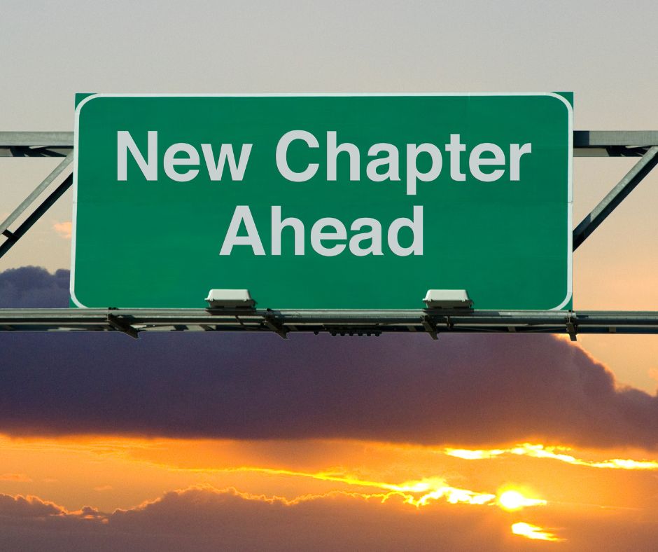 A road sign reads "New Chapter Ahead," against a sunrise.